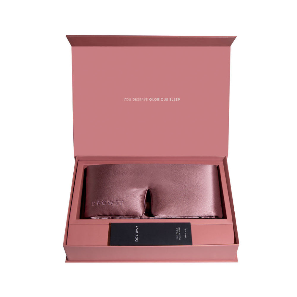 Pink sleep mask and pillow spray in a box with text on a white background.