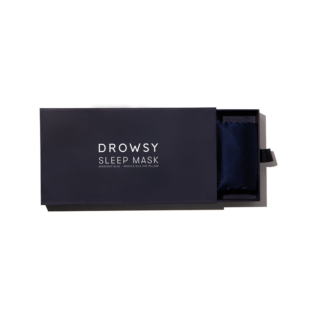 Navy blue sleep mask in a box with a white background