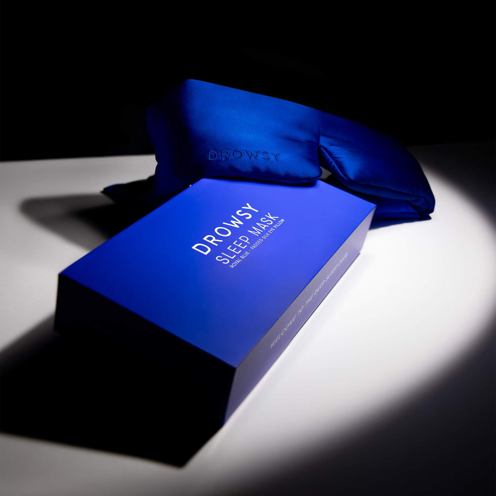 Royal Blue sleep mask and packaging on a dark background with white spotlight on product