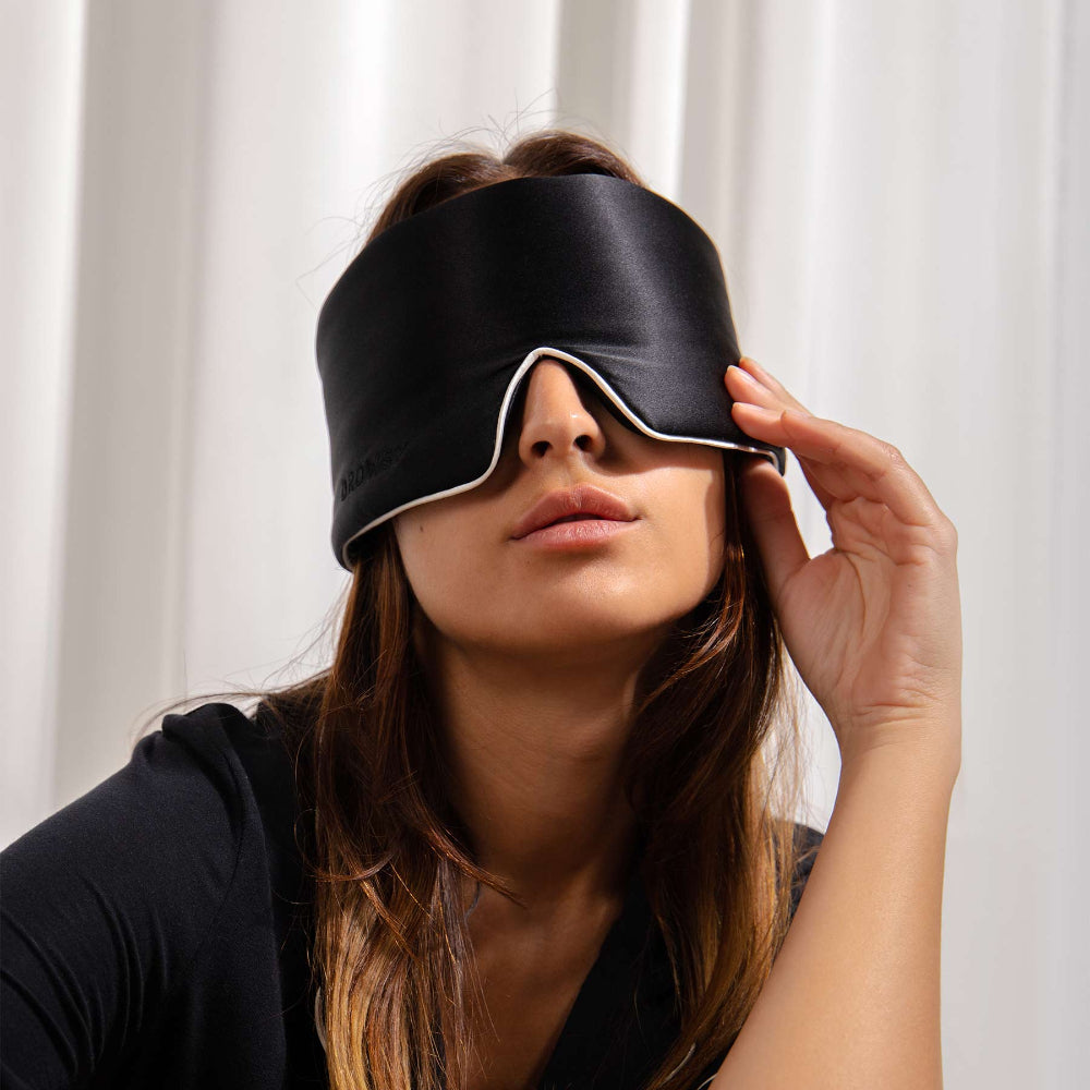 Person wearing a black sleep mask against a white background