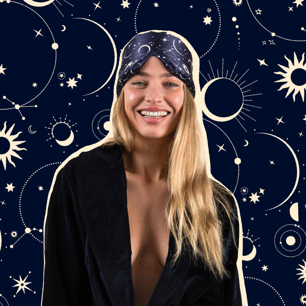 Woman wearing a star-patterned Cosmic Energy Sleep mask against a celestial background