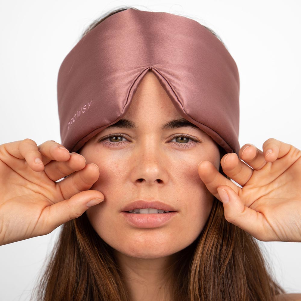 Woman wearing on her forehead a Drowsy Damask Rose pink silk sleep mask
