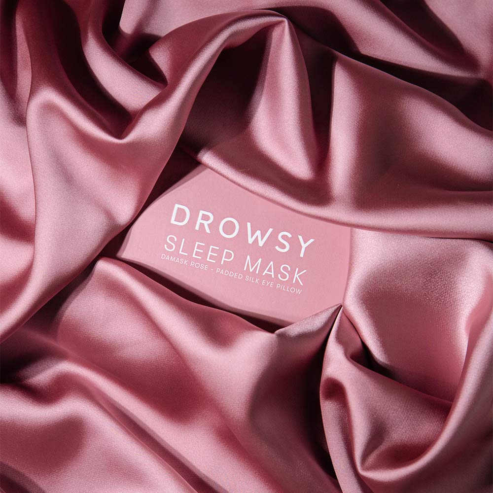 Drowsy Damask Rose Pink sleep mask packaging on draped pink fabric