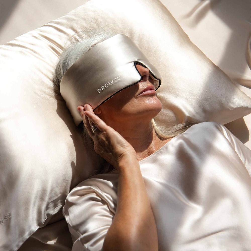 Person lying in bed wearing a Dusty Gold Piping Dream sleep mask on a dusty gold pillowcase.