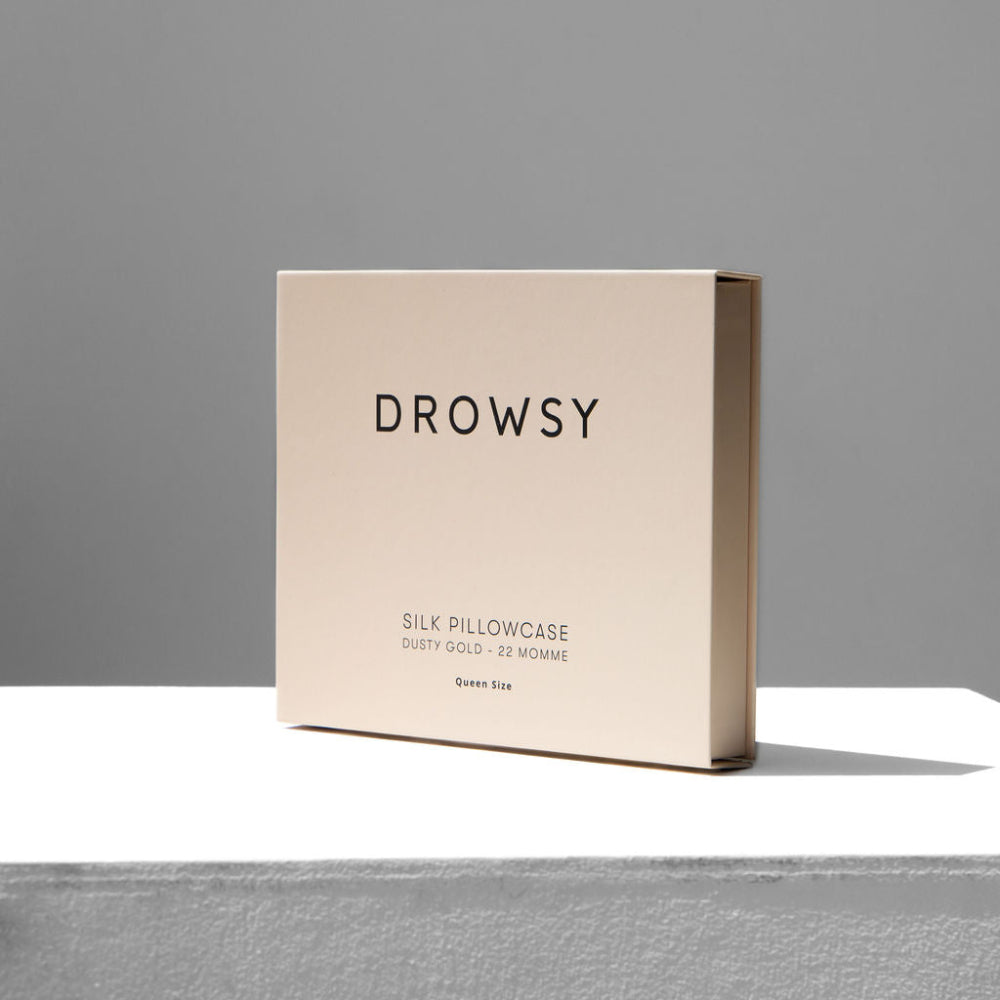 Beige box with 'DROWSY' branding and Dusty Gold pillowcase inside on a neutral background