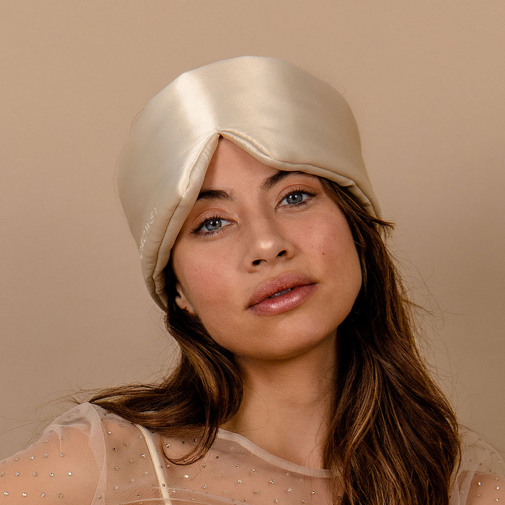 Woman wearing a Drowsy dusty gold sleep mask against a neutral background