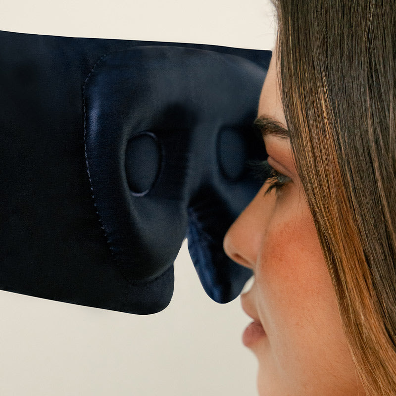 Person placing a silk sleep eye mask with eyelash cocoon closer to face