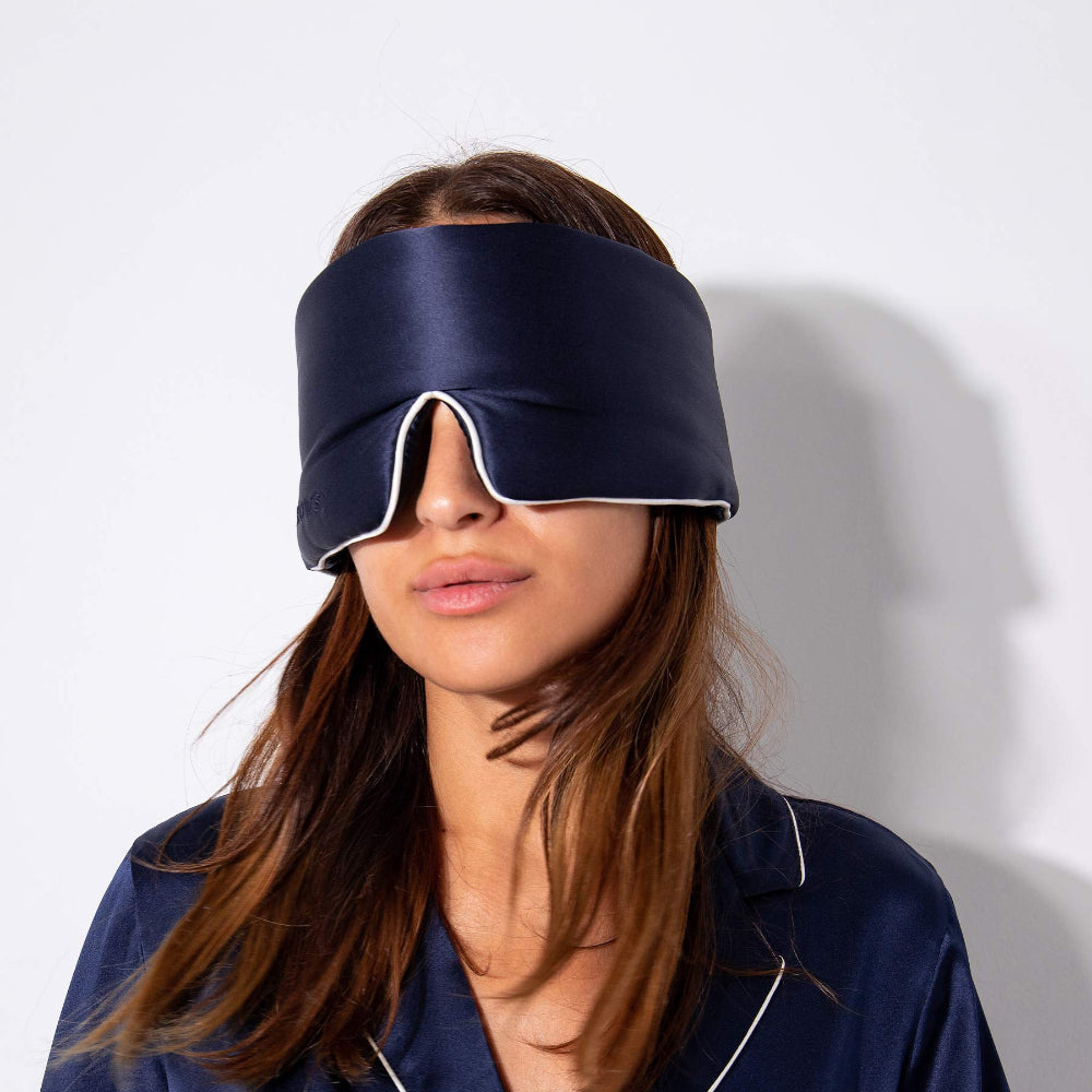 Person wearing a Midnight blue sleep mask and pyjamas on a white background