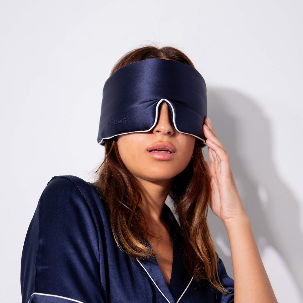 Person wearing a navy blue sleep mask and matching robe against a white background.