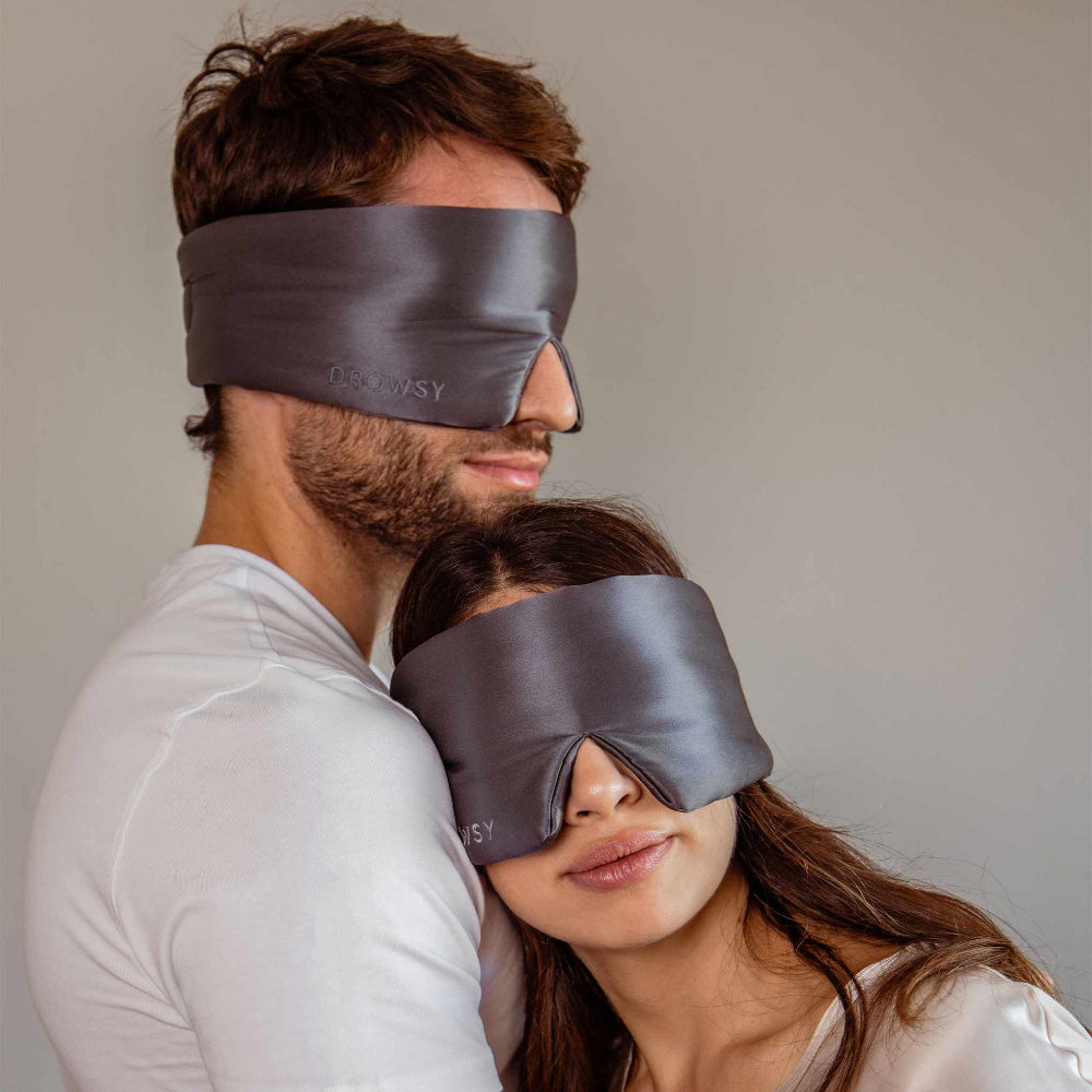 Man and woman wearing grey silk sleep masks.