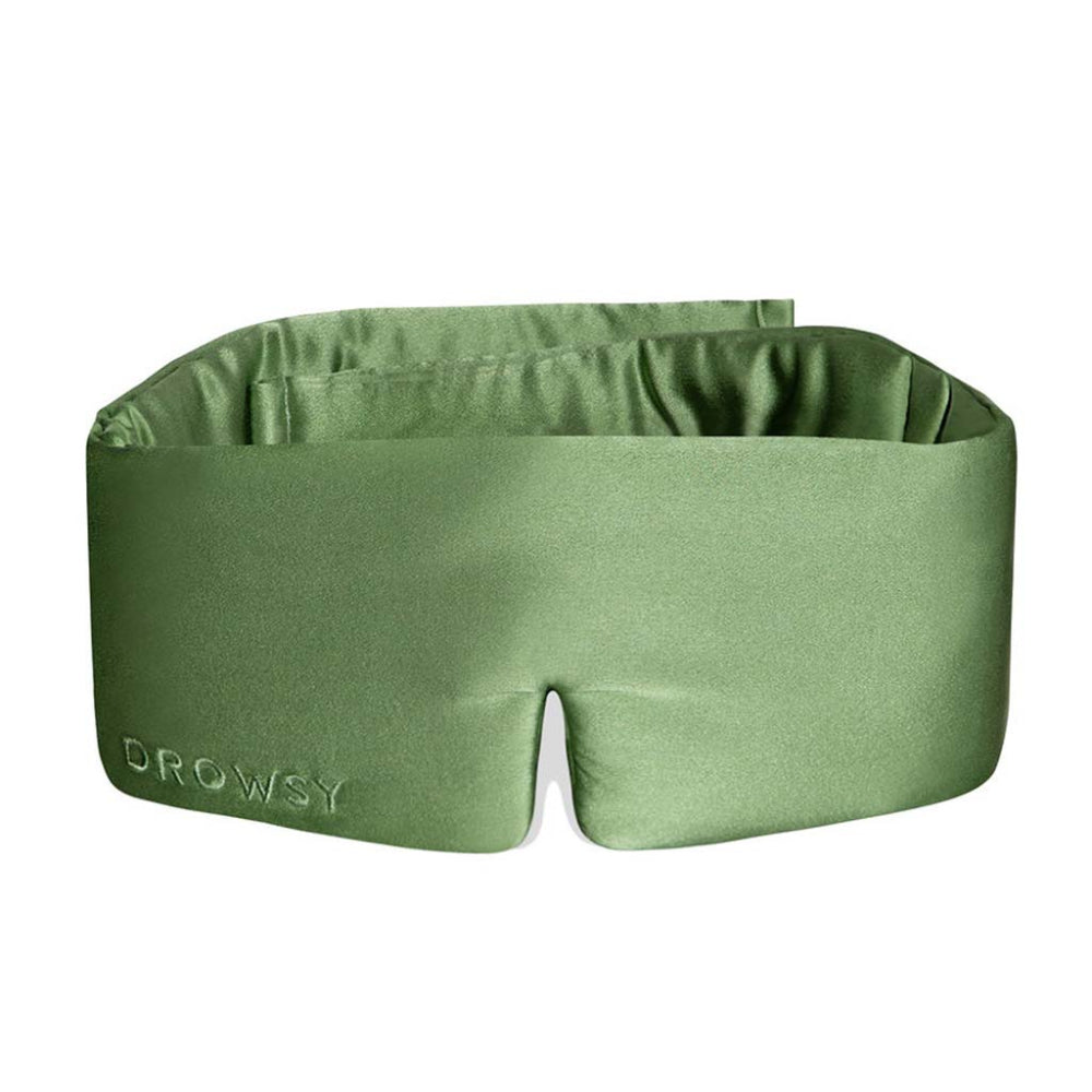 A pistachio green silk sleep mask with a fully adjustable design, featuring the brand name 'DROWSY' on the front.