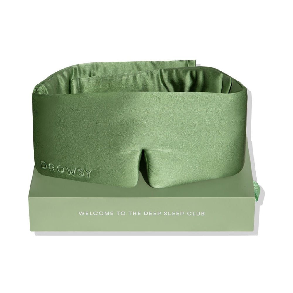 Green sleep mask on top of box packaging on a white background