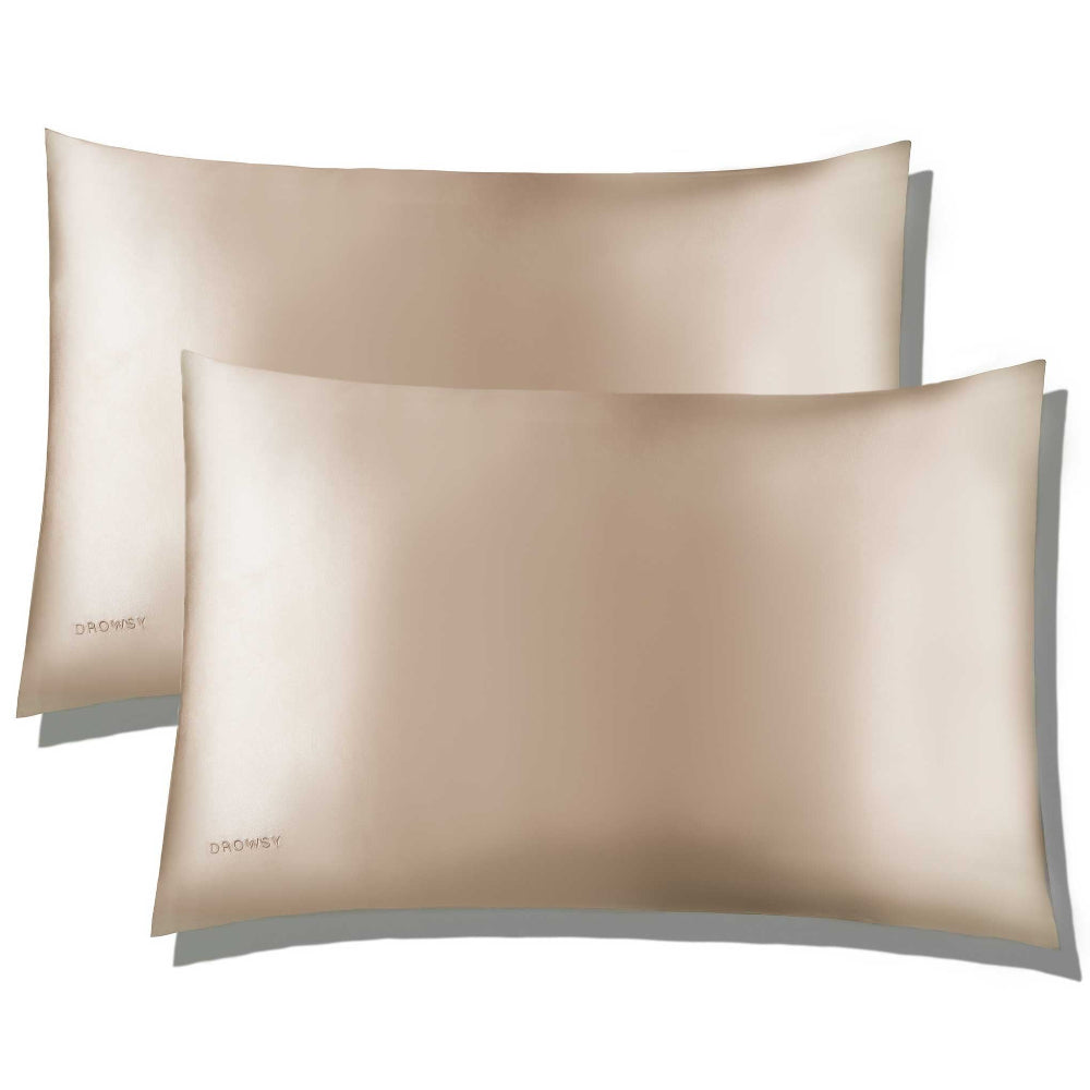 Two dusty gold silk pillowcases with a luxury envelope closure on a white background