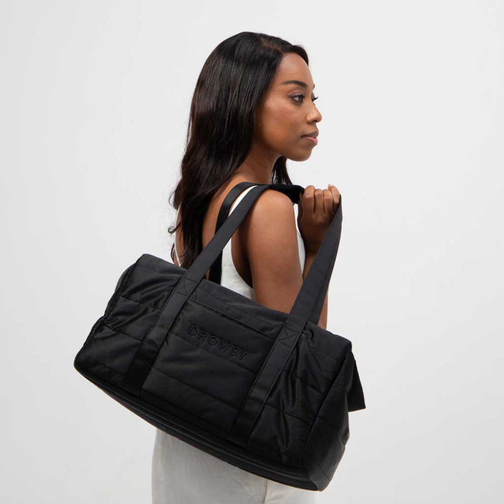 Woman carrying a black duffel bag on a white background