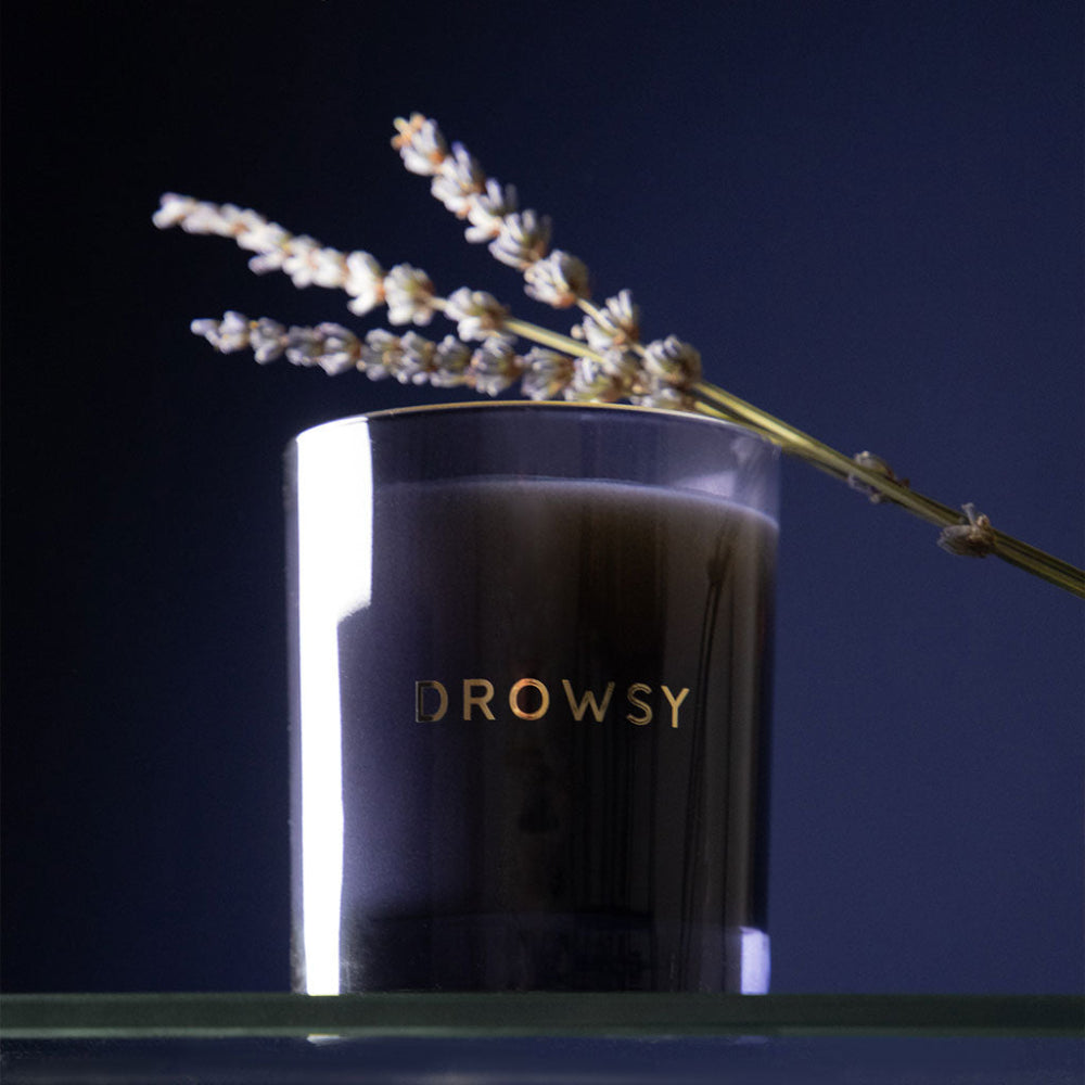 Black candle labelled 'Drowsy' with a branch on a dark background