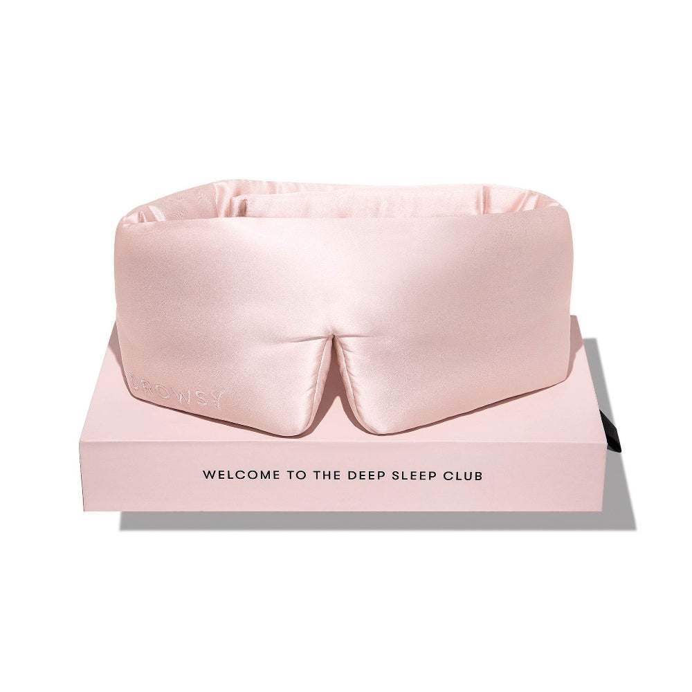 Pink silk sleep mask on a pink box with text 'Welcome to the Deep Sleep Club'.