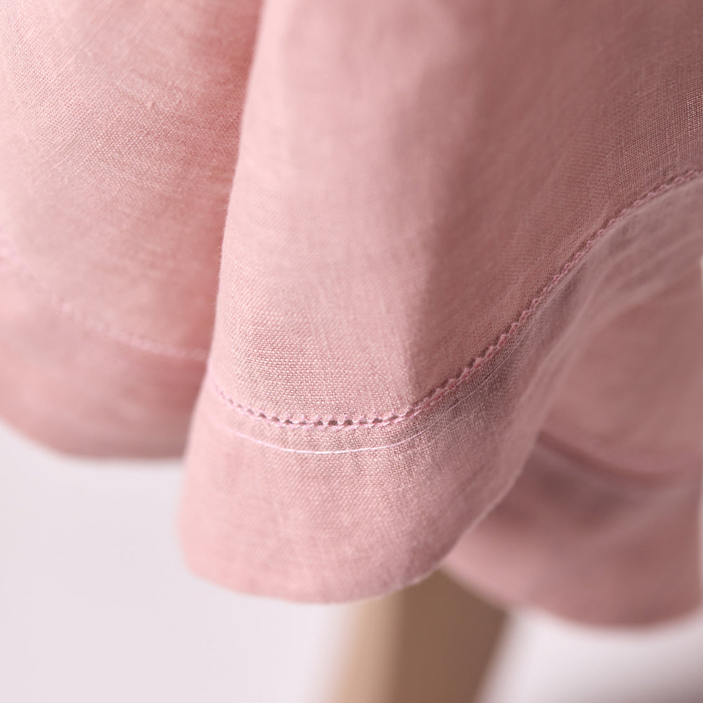 Close-up of a pink hemstitched tablecloth with a white background