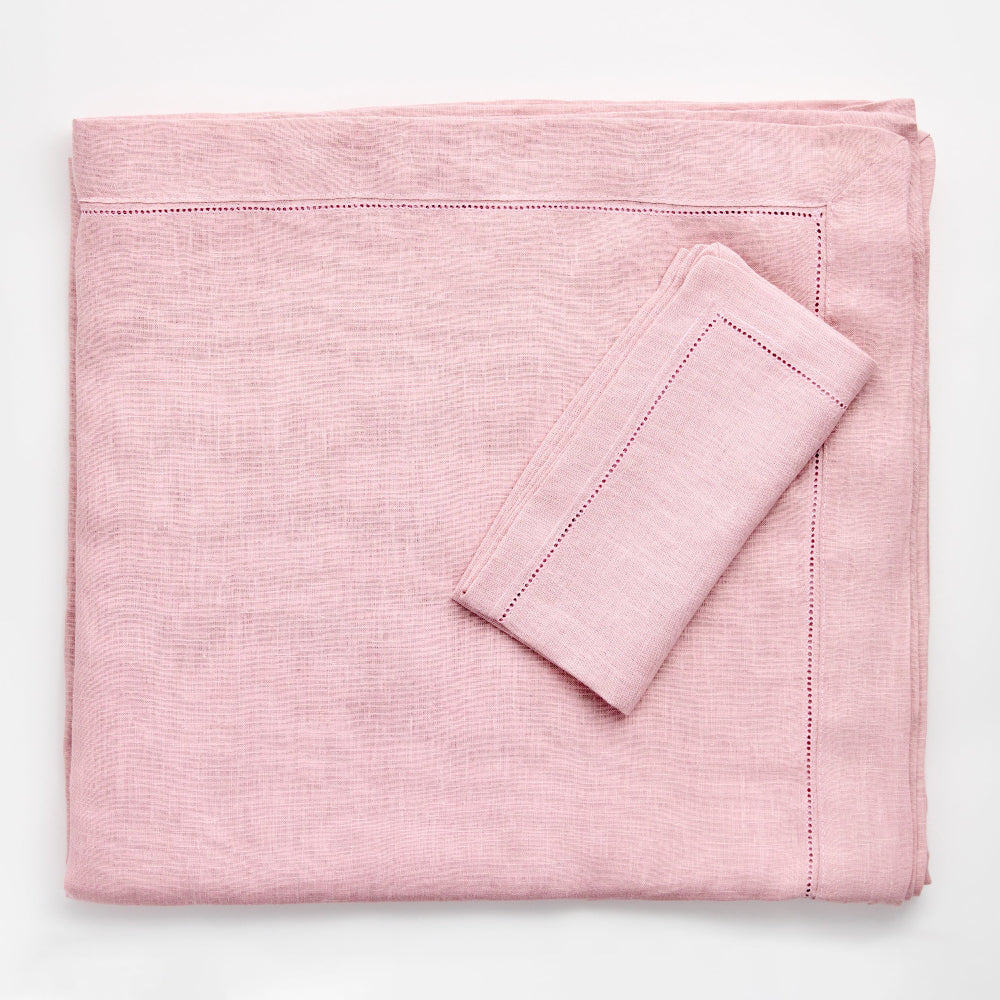 Pink folded tabelcloth and pillowcase on a white background