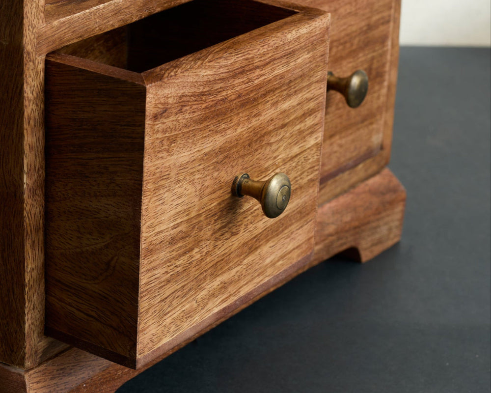 Wooden drawer with brass handles on a dark surface
