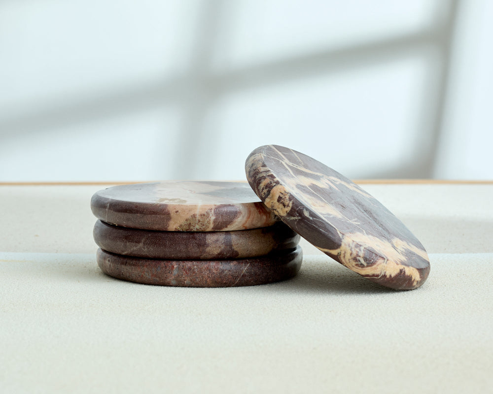 Stack of brown stone coasters on a light surface with a blurred background