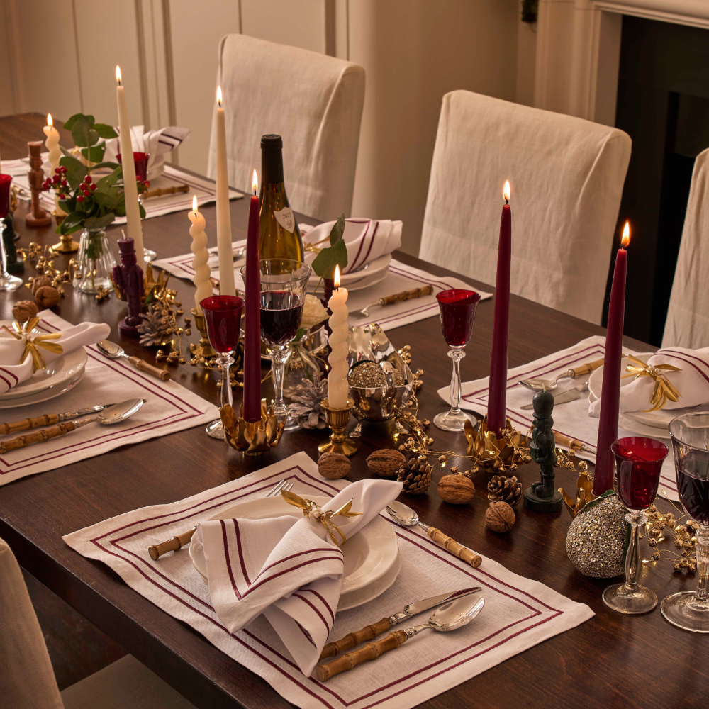 Decorative dinner table set with candles, wine glasses, and place settings in a warm indoor setting.