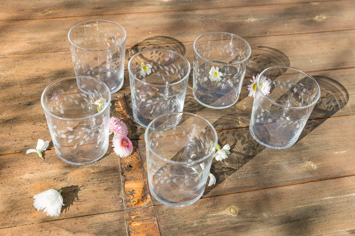 Clear glass tumblers with flowers on a wooden surface