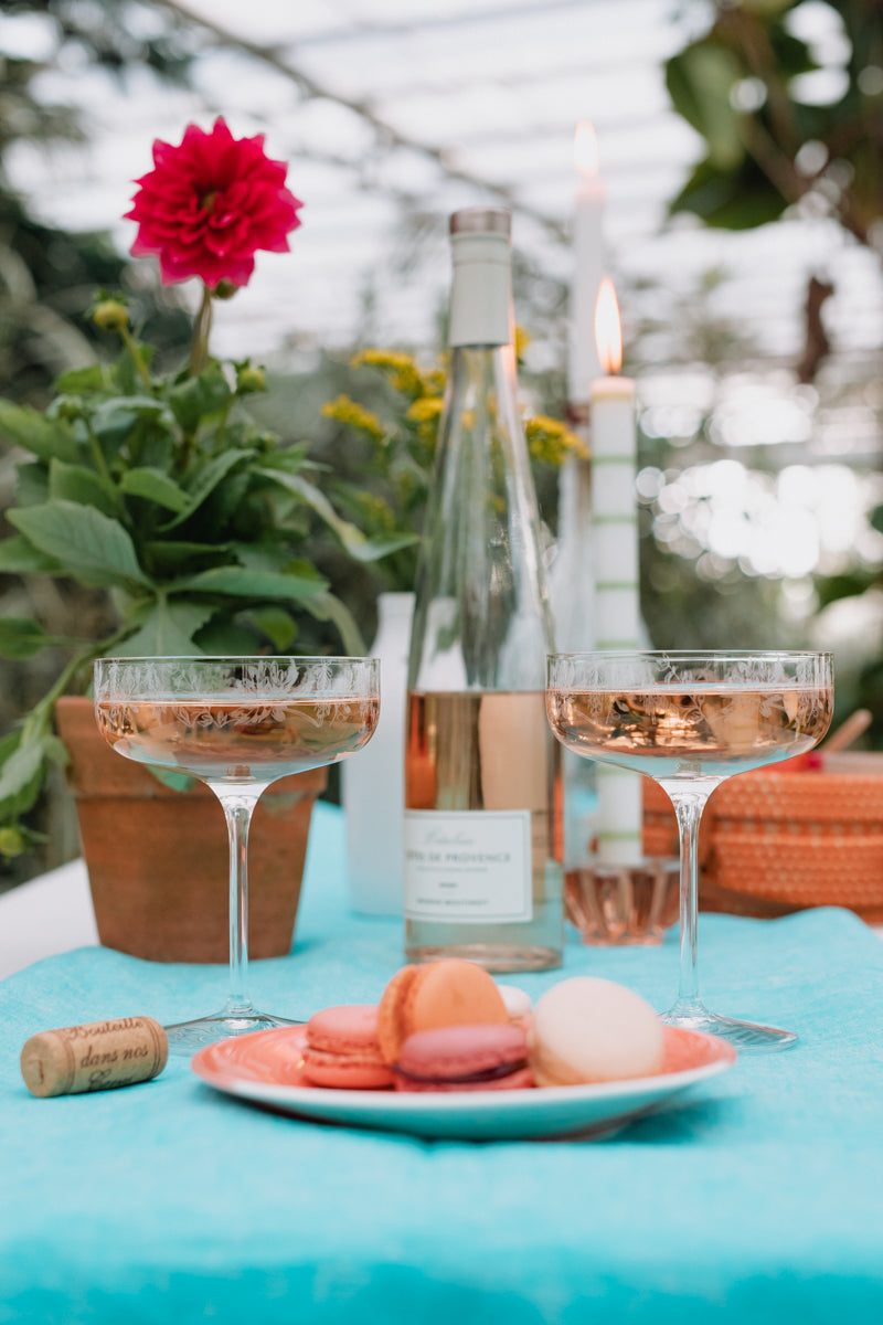 Outdoor setting with wine glasses, bottle, and macarons on a blue tablecloth.