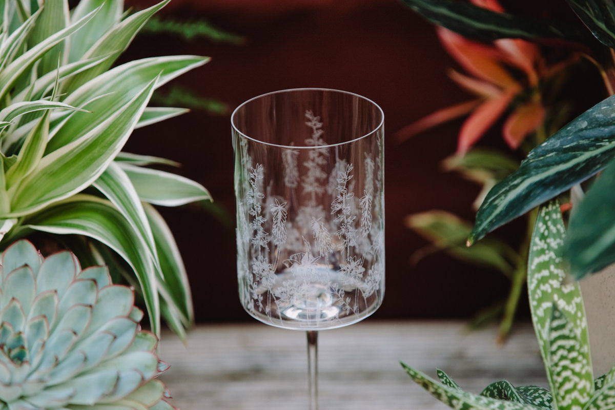 Clear glass with engraved design on a blurred plant background