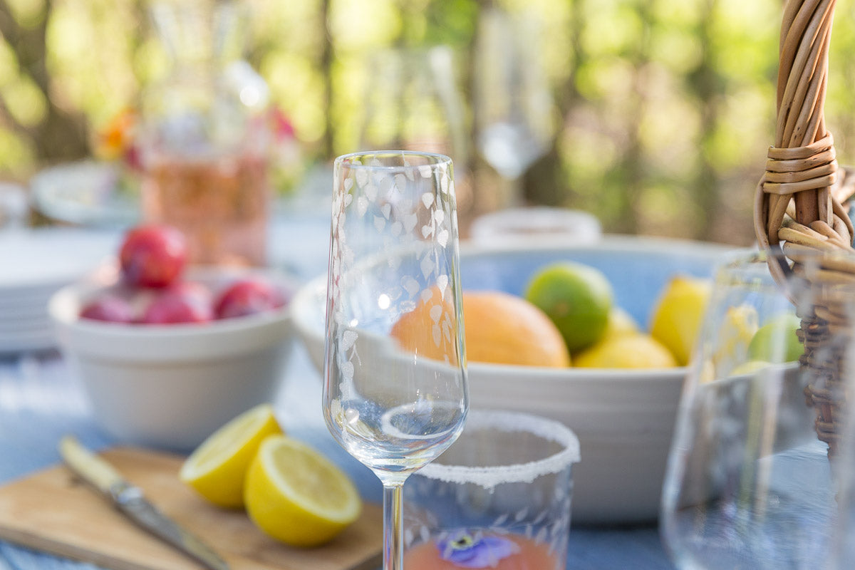 Champagne glass on a table with fruit and a blurred outdoor background