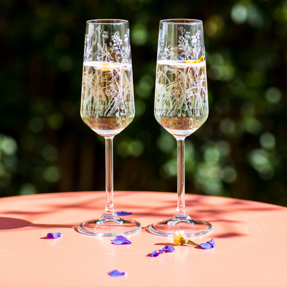 Two champagne flutes with floral patterns on a table outdoors.