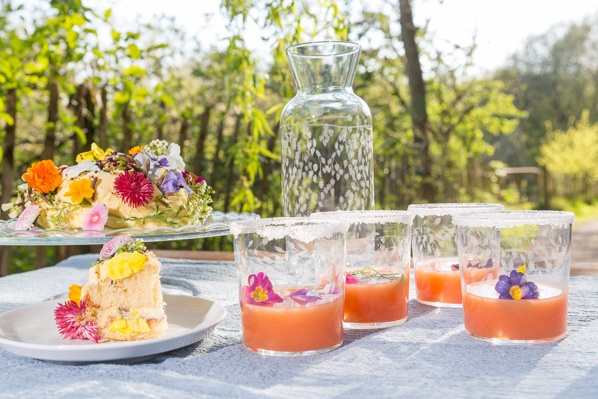 Outdoor setting with floral cakes and drinks on a table