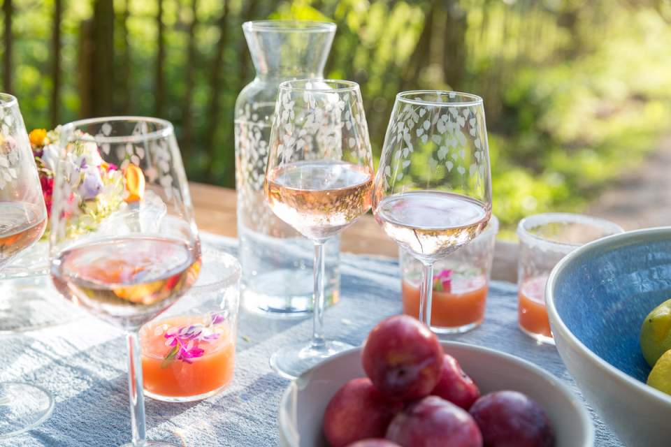 Outdoor setting with wine glasses, a carafe, and fruit on a table.