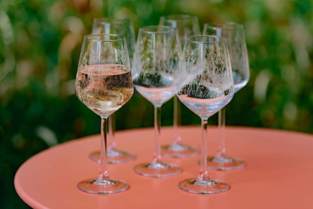 Set of wine glasses with white wine on a pink table outdoors