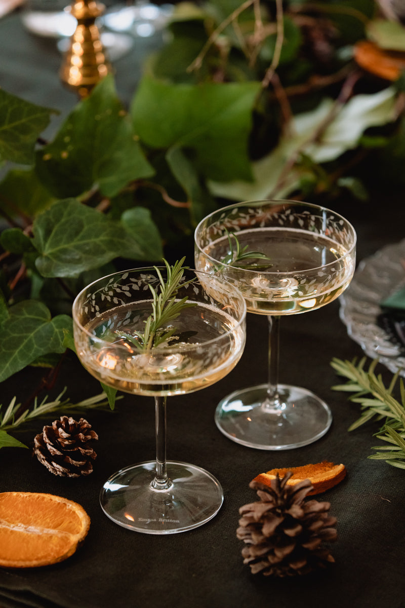 Two cocktail glasses with a dark background and decorative elements.