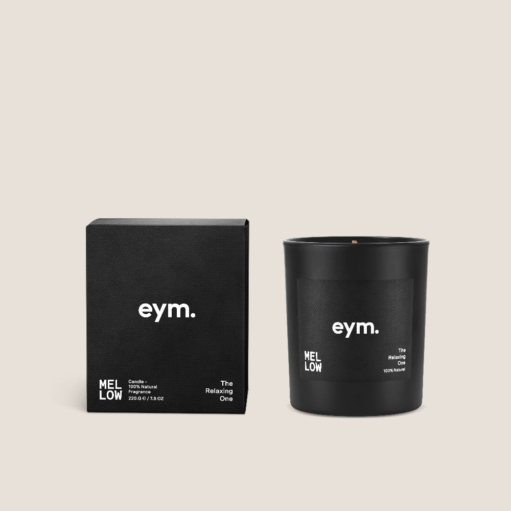 Black candle vessel with 'eym.' branding next to its packaging on a beige background