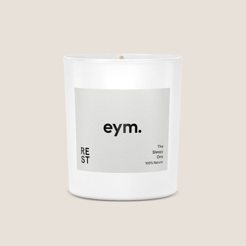 White candle with a grey 'eym' label on a beige background