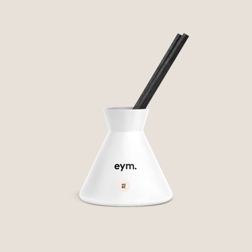 White diffuser called HOME with black reeds on a beige background, featuring the brand 'eym'.