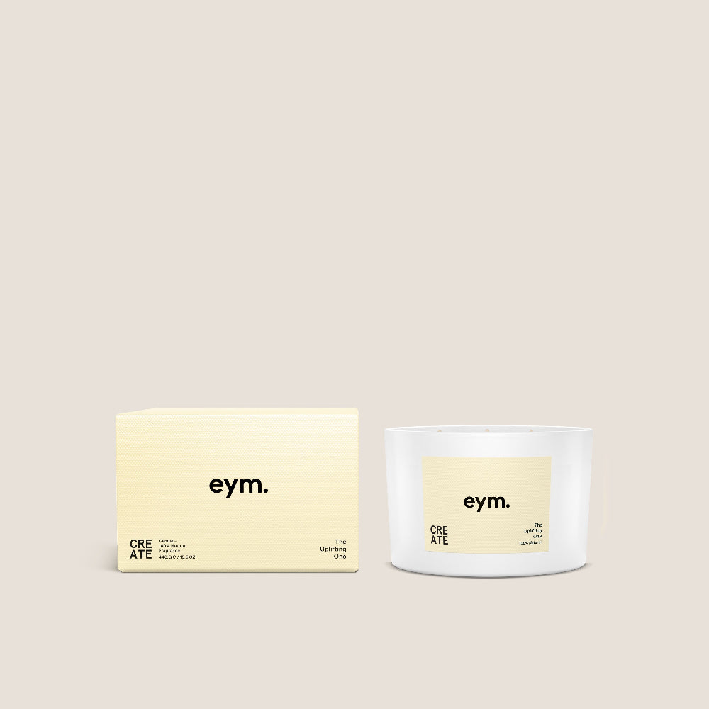 White candle and yellow packaging with 'eym.' branding on a beige background