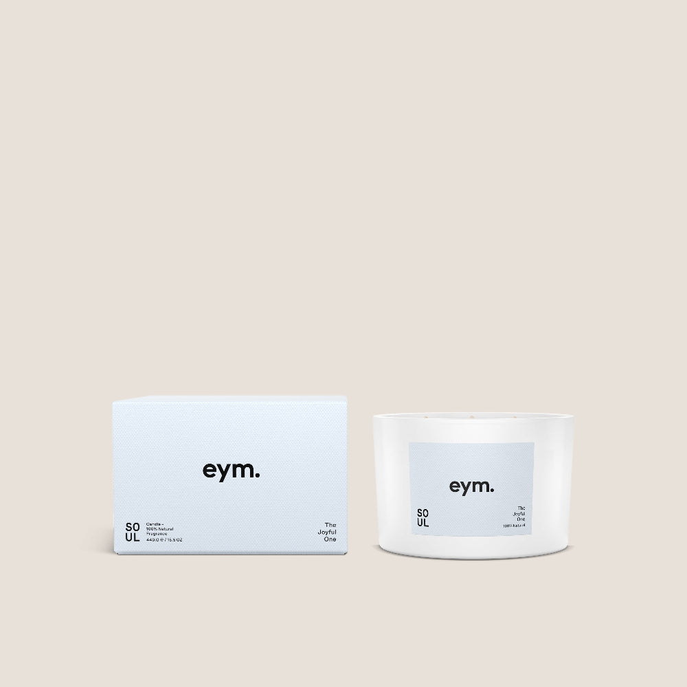 White Candle and packaging with 'eym.' branding on a beige background