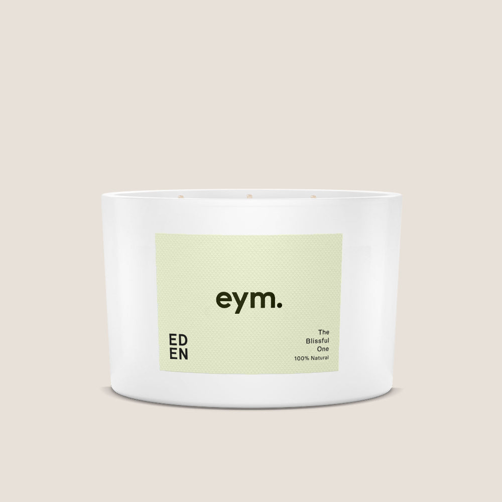 White candle called 'EDEN' with a green label featuring 'eym.' on a beige background