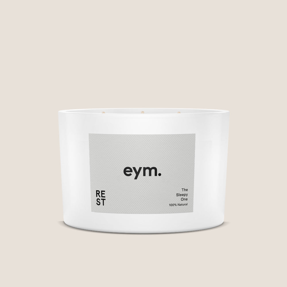 Three wick White candle container with 'eym.' label on a beige background