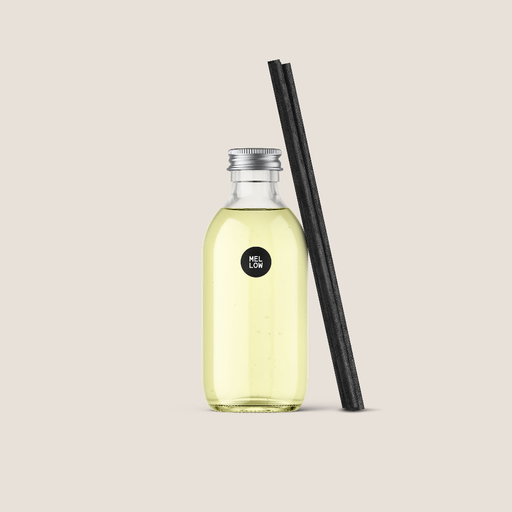 Eym Refill diffuser called 'Mellow' in a Clear bottle with yellow liquid and black reeds on a beige background