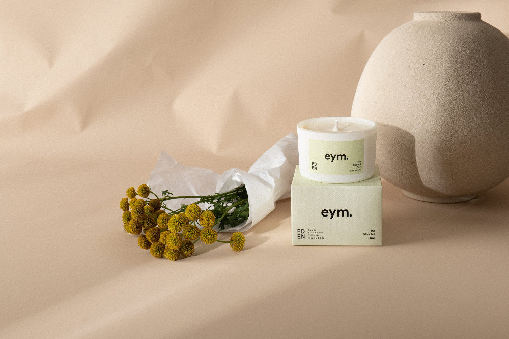 eym product packaging with a candle and flowers on a beige background