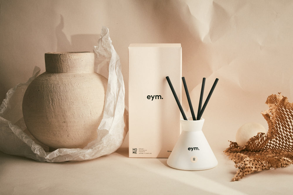 Decorative items including a vase, diffuser, and packaging with 'eym.' branding on a neutral background.