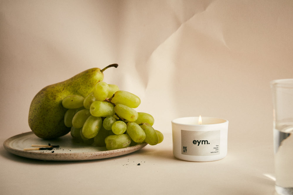 Grapes and Pear on a plate and a candle called Rest on a table with a neutral background