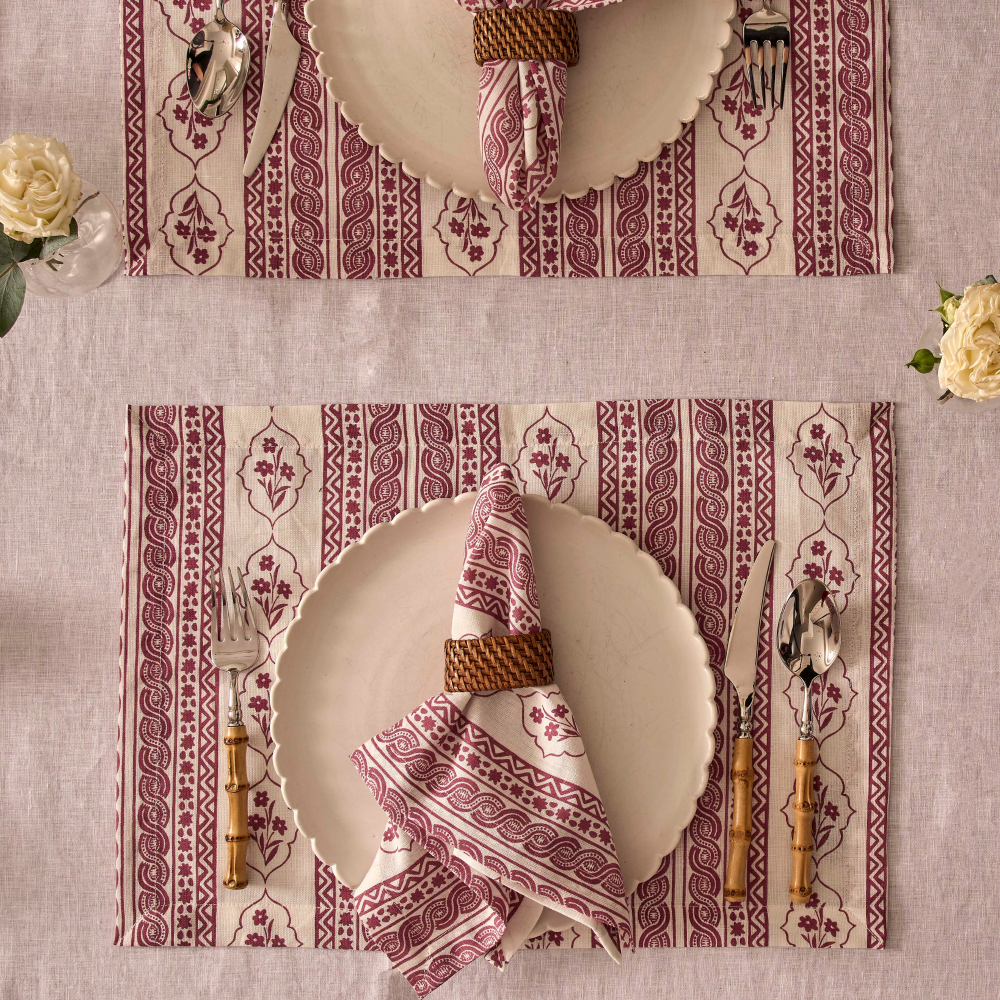 Table setting with patterned placemats, plates, and cutlery on a textured surface.