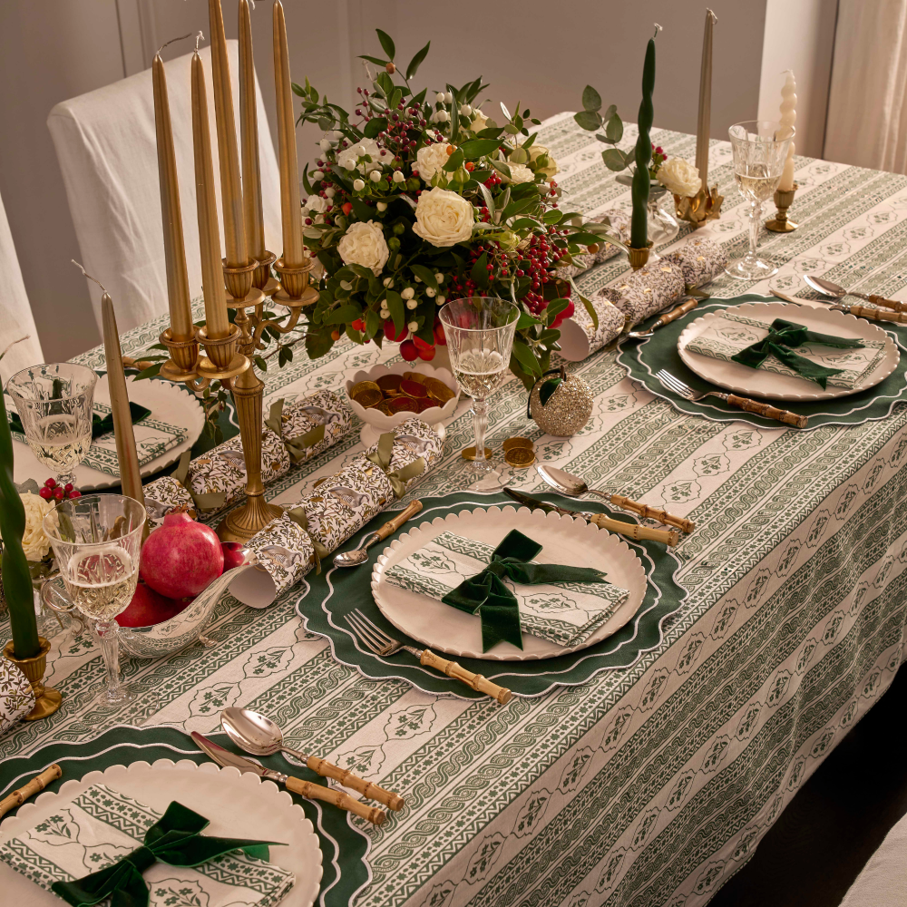 Elegant table setting with floral centerpiece, candles, and patterned tablecloth.