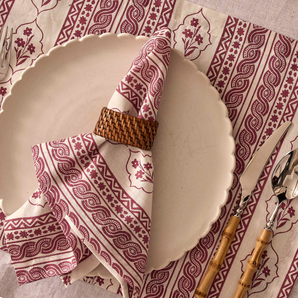 Plated dish with a folded napkin and cutlery on a patterned tablecloth
