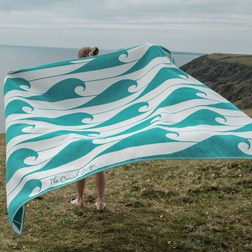 Person holding a teal and white wave-patterned towel outdoors
