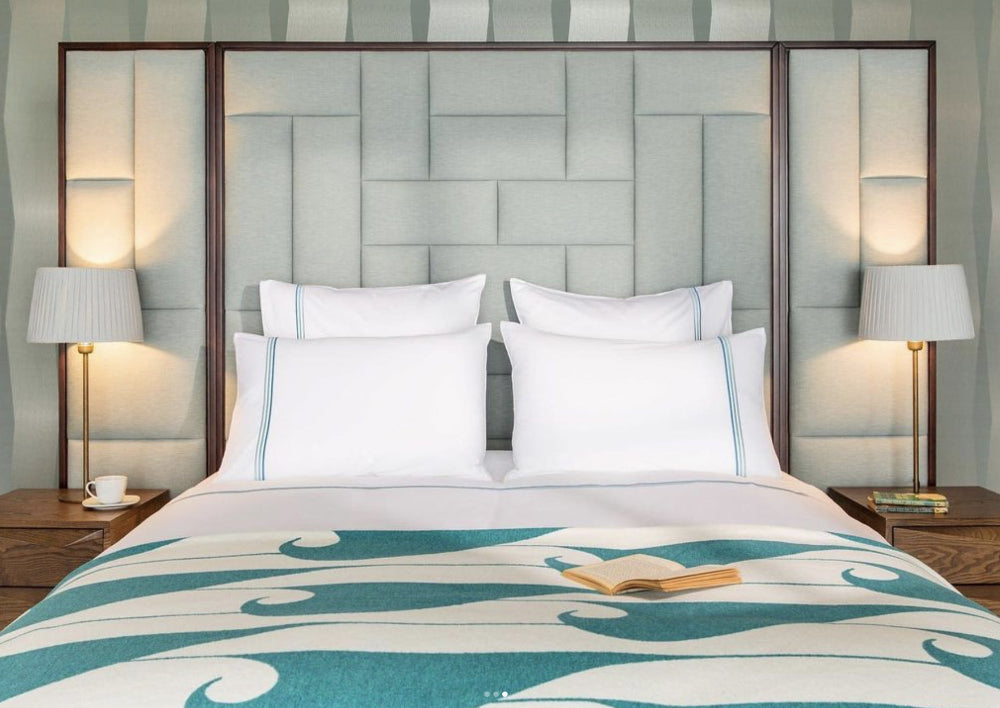 Bedroom with a bed featuring a patterned Blanket, white pillows, and two lamps on either side.